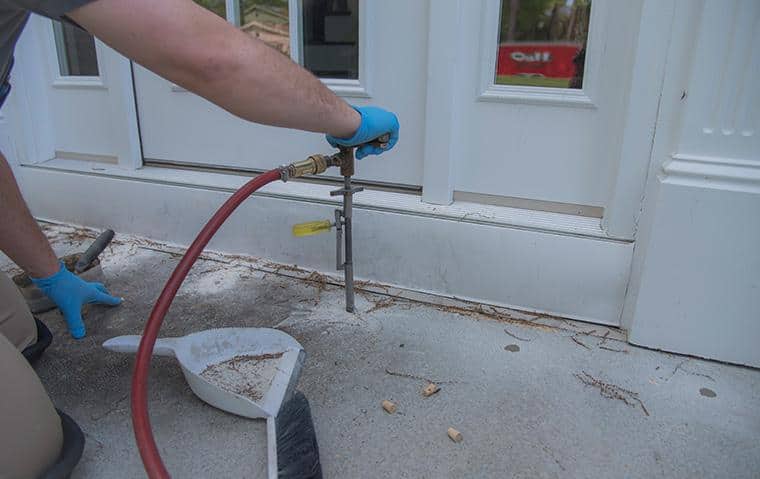 a technician performing a liquid treatment for termites outside a new york home