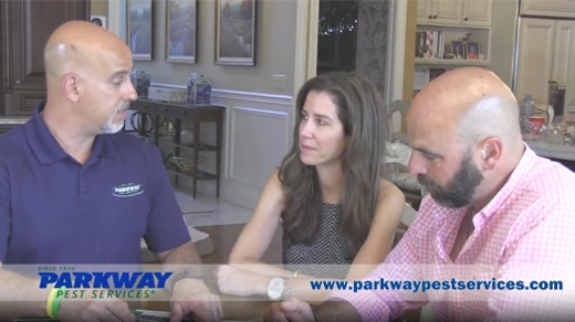 A technician is sitting and talking to two homeowners.